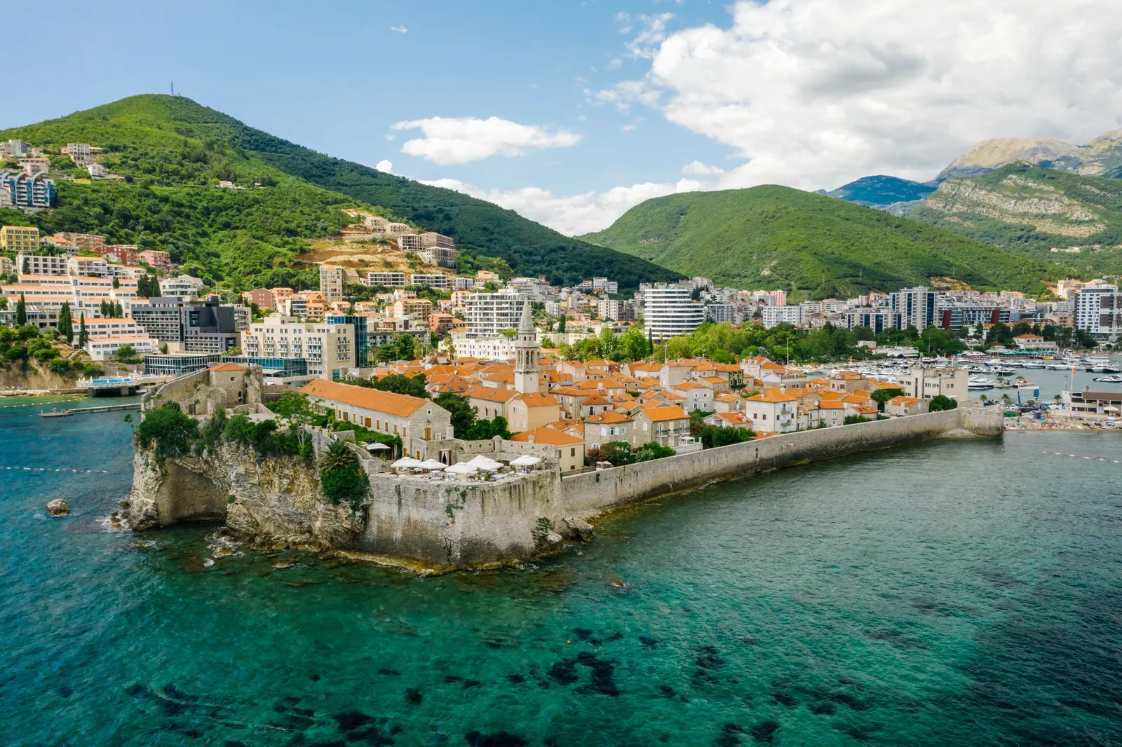 Widok z lotu ptaka na otoczone murami Stare Miasto Budva na skalistym półwyspie obok mariny na Adriatyku